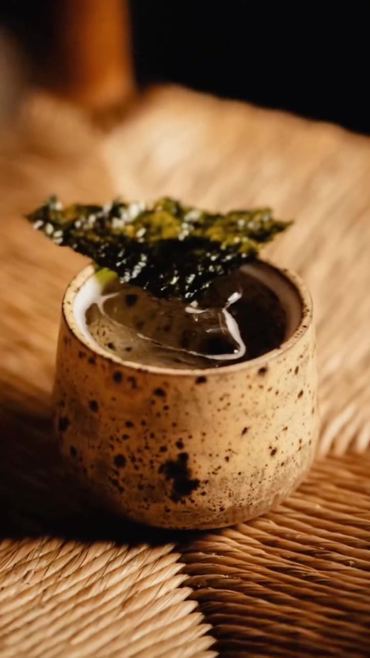 A speckled ceramic cup garnished with crisp nori