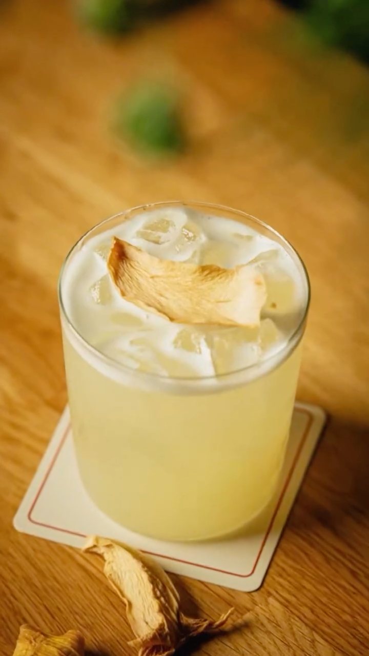 A pale sour over ice on a paper coaster
